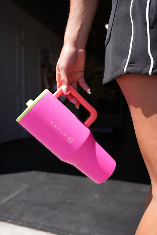Person carrying a pink 40 oz insulated traveler tumbler with handle and straw lid, designed for everyday hydration, travel, workouts, and on-the-go use.