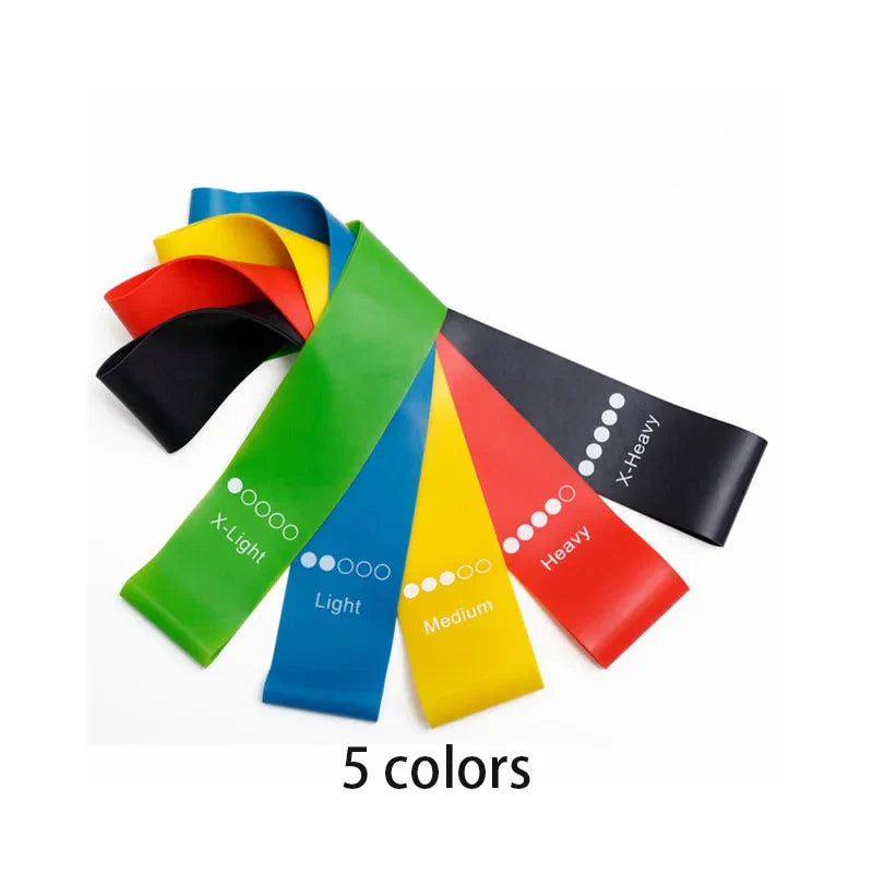 Five color-coded TPE resistance loop bands arranged in a fan display, featuring extra light, light, medium, heavy, and extra heavy resistance levels for strength training, stretching, yoga, Pilates, mobility, and home fitness workouts.