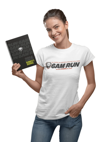 Smiling woman wearing a white 6AMRun T-shirt while holding the 6AMRun 52-Week Runner's Journal, showcasing the running journal and brand apparel for runners and fitness enthusiasts.