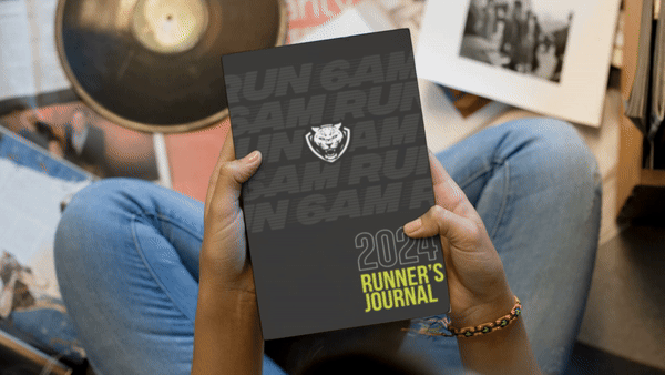 Short Video Clip of a Person holding the 6AMRun Runner's Journal while seated, showcasing the journal cover in a lifestyle setting designed for runners to track workouts, training plans, race goals, and running progress.