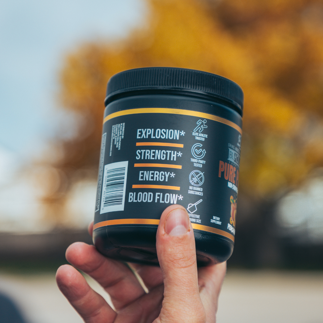 Hand holding a supplement jar with text on a blurred natural background