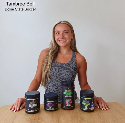 BlackLabel Sports ambassador Tambree Bell of Boise State Soccer posing behind a display of Performance Greens, Pre Game, Pure Hydrate, and Creatine supplements on a wooden table.
