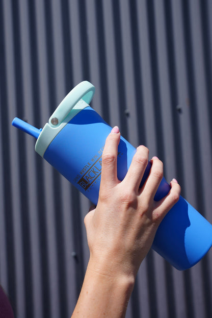 Hand holding a blue BLACKLABEL 32 oz insulated sport cup with flip straw and carry handle, designed for convenient hydration during workouts, travel, and everyday use.