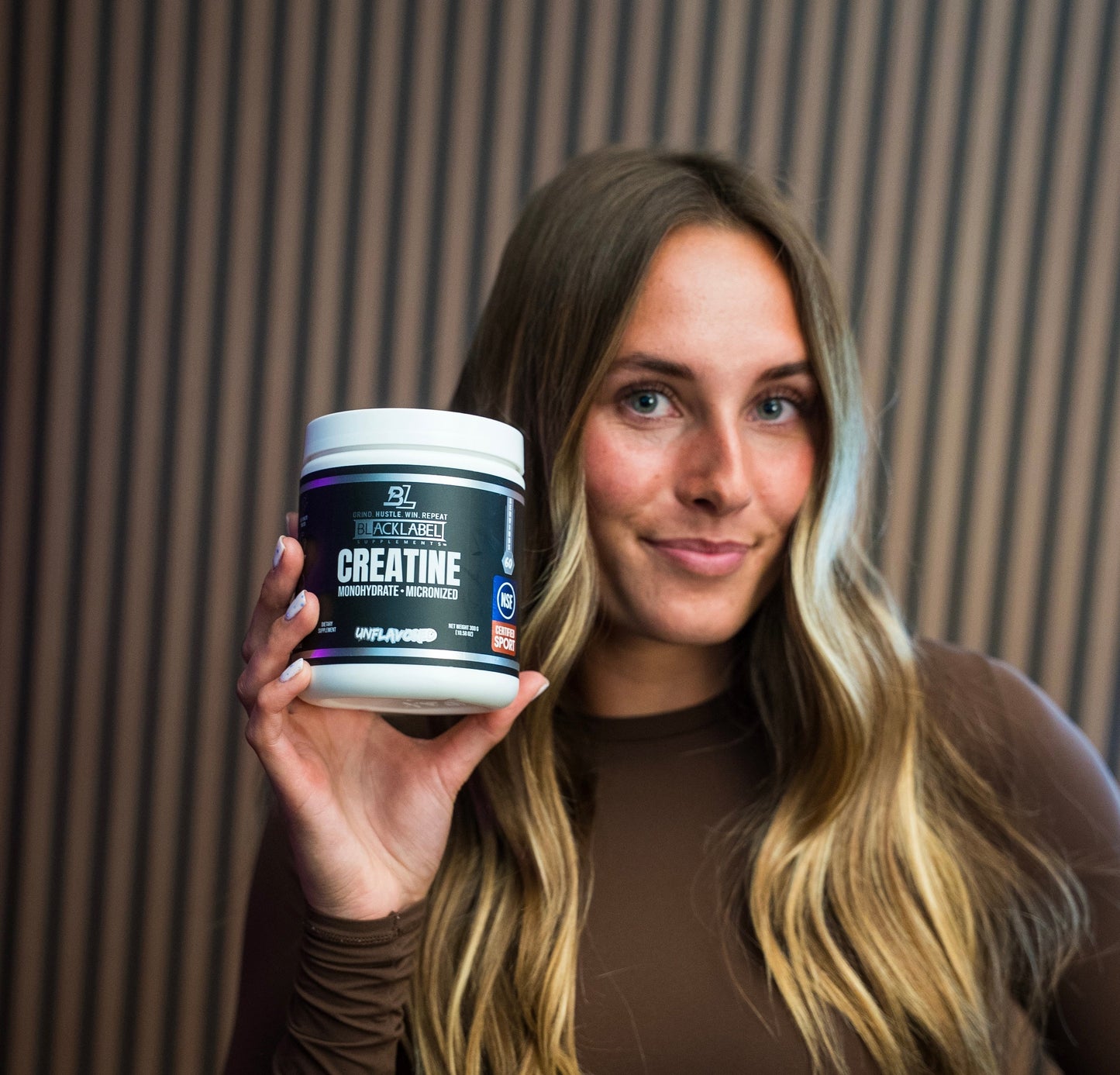 Woman holding a container of creatine supplement with a blurred background