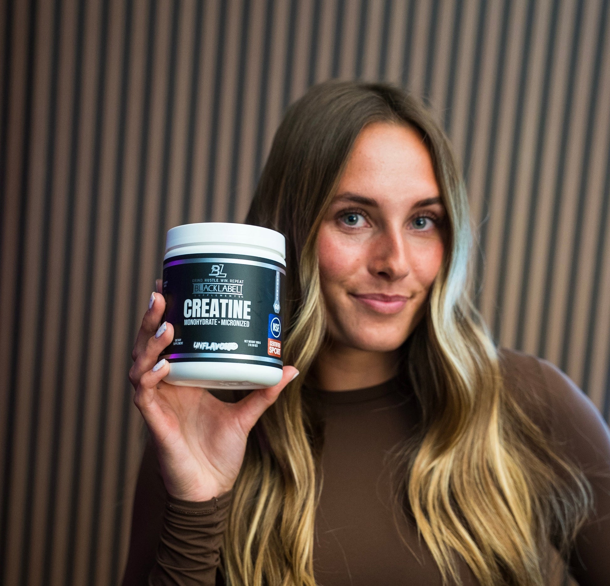 Woman holding a container of creatine supplement with a blurred background
