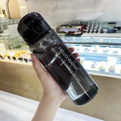 Black 780ml sports water bottle with flip-top lid and built-in straw held in a casual indoor setting