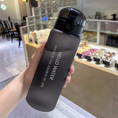 Black 780ml sports water bottle with matte finish and flip-top lid held indoors