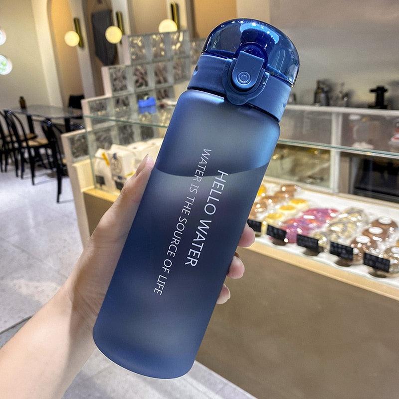Blue frosted 780ml sports water bottle with matching flip-top lid and built-in straw held indoors