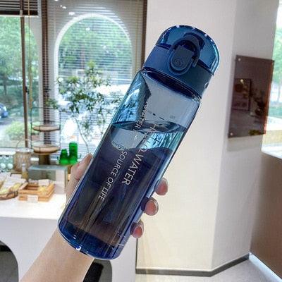 Blue 780ml sports water bottle with flip-top lid and built-in straw held indoors