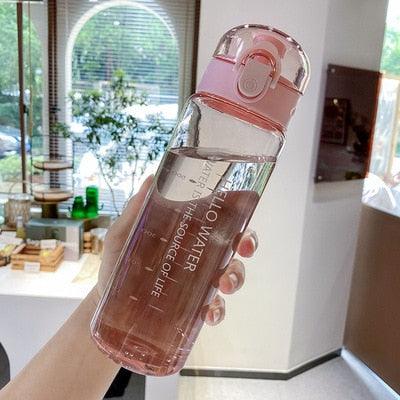 Pink 780ml sports water bottle with flip-top lid and built-in straw held indoors