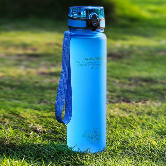 Blue water bottle with a handle on grass